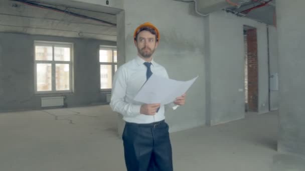 Будівельник досліджує нову будівлю. Бізнесмен у костюмі оглядає незакінчену будівлю . — стокове відео