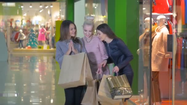 Tres hermosas mujeres jóvenes emocionadas con bolsas de compras en una tienda . — Vídeo de stock