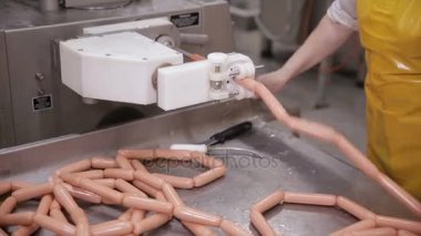 Yiyecek fabrikası. İşçi otomatikleştirilmiş gıda üretiminde sosis üretiyor.