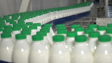 Süt üzerinde konveyör taşıma şişelerde. Süt süt fabrikası'nda bir Konveyör bant üzerinde yeşil kapakları.