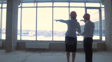 İş adamı ve iş kadın takım, yeni bir bitmemiş iş yeri zor şapka iletişim kurmak, tartışmak plan, şantiye.