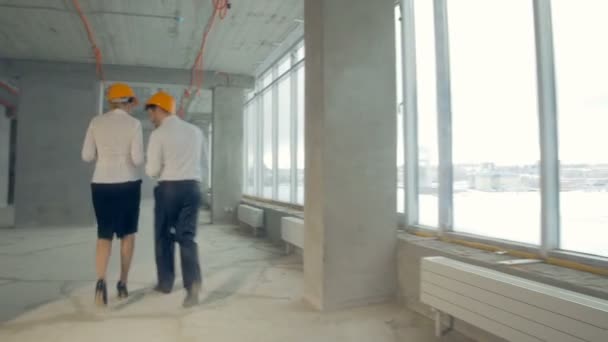 Equipo de negocios irreconocible, ingenieros, agentes inmobiliarios en trajes que trabajan en un sitio de construcción, edificio sin terminar. Por detrás. Steadycam tiro . — Vídeo de stock