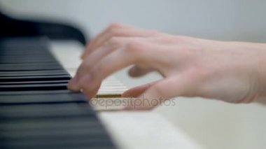 Yakın çekim. Kadın müzisyen bir grand piyano çalan eller.