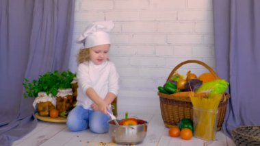 Sevimli küçük kız Şef yemek sağlıklı yemek sebze ve pan kullanarak.