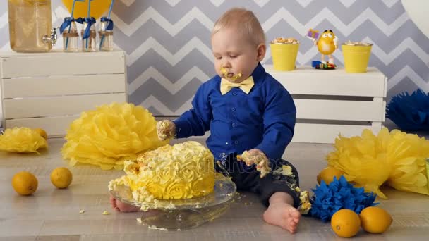 Adorable garçon d'un an dévorant gâteau avec ses mains . — Video