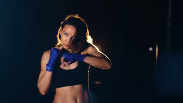 Mujer joven y segura en guantes de boxeo boxeo mirando a la cámara . — Vídeos de Stock