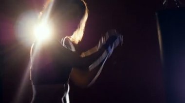 Genç kadın karanlıkta boks. Kadın siluet Shadowboxing yapma. Onun arkasında güçlü bir ışık.