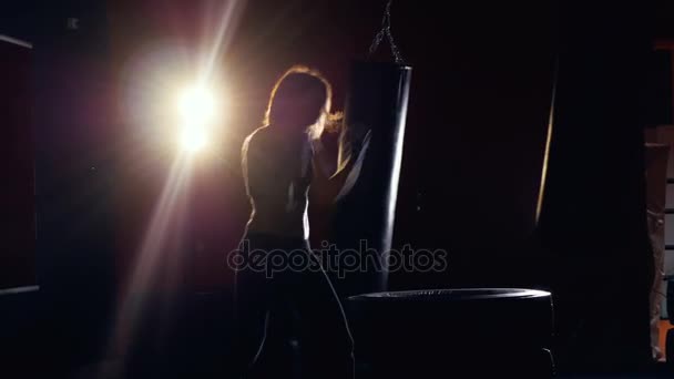 Silueta femenina haciendo shadowboxing. Mujer joven boxeando en la oscuridad. Bengalas de lente . — Vídeo de stock