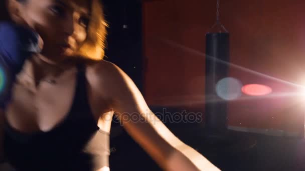 Ung atletisk kvinna boxning i mörka studio. Steadicam skott. — Stockvideo
