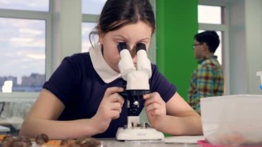 Mikroskop mikroskop bakarak okul araştırma laboratuarında ile genç kız.