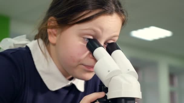 Chica joven con microscopio en el laboratorio de investigación de la escuela mirando al microscopio . — Vídeos de Stock