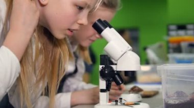 Genç öğrenciler okul araştırma laboratuarında mikroskop bakarak okul.