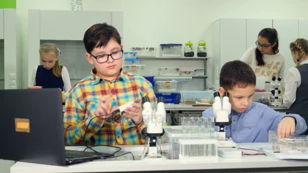 Concetto scientifico scolastico. Bambini che studiano microscopio, biologia studing, chimica nel laboratorio scolastico. Primo piano . — Video Stock