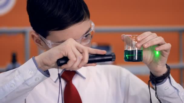 Μαθητής στο σχολείο να κάνει ένα επιστημονικό πείραμα χρησιμοποιώντας αντιδραστήρια, δοκιμαστικό σωλήνα και λέιζερ. — Αρχείο Βίντεο