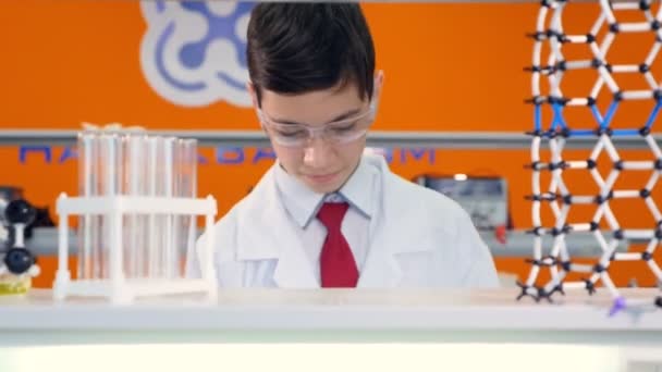 Menino do ensino médio misturando líquidos em tubo de ensaio na aula de ciências . — Vídeo de Stock
