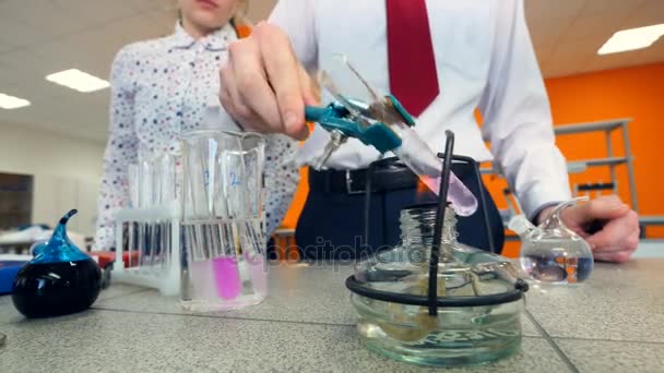 Grundskoleelever som värme ett provrör som gör kemi experiment i en science klassrummet. — Stockvideo