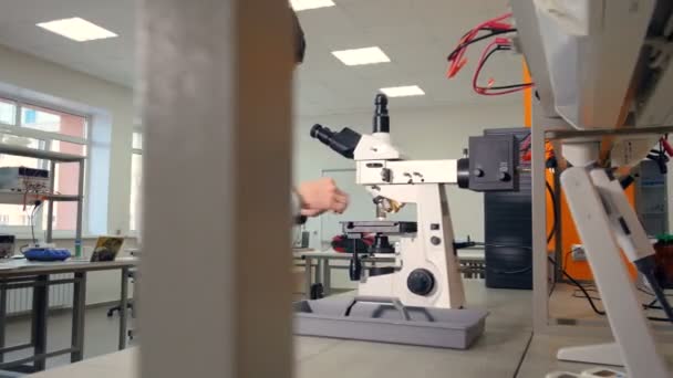 Jongen van de middelbare school op Microscoop in een laboratorium school biologie onderzoek te maken. — Stockvideo