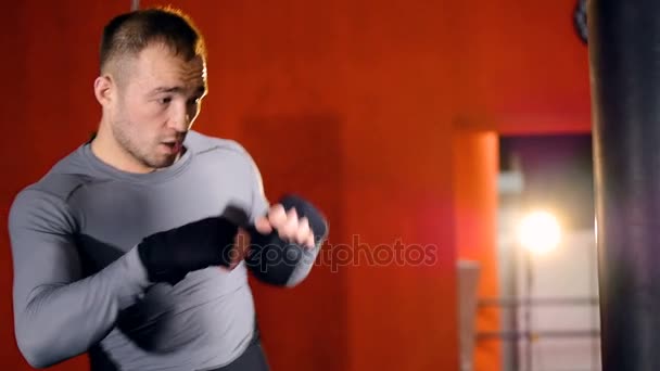 Stark idrottsman träffar en boxningssäck. Slow motion. — Stockvideo