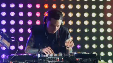 Bir gece kulübünde pikaplar arkasında çekici erkek Dj.