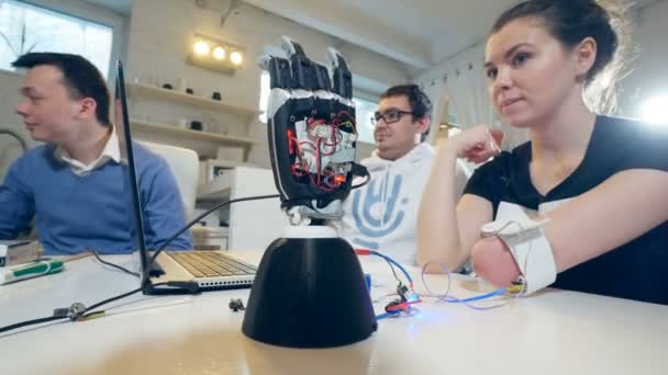 La ragazza sorridente sta girando la sua mano amputata e la mano del robot sta contemporaneamente aprendo il palmo . — Video Stock