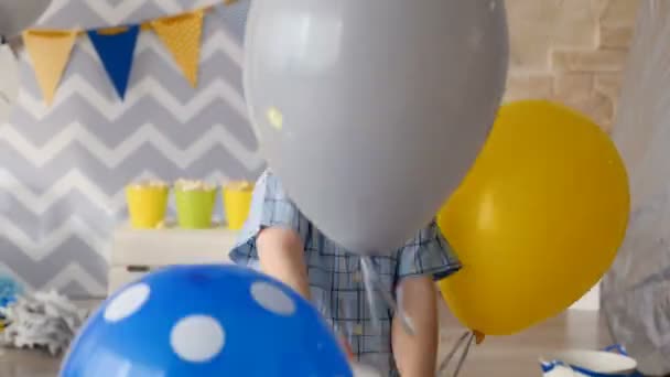 Счастливый ребенок играет с голубыми и серыми шариками, подаренными ему на день рождения . — стоковое видео