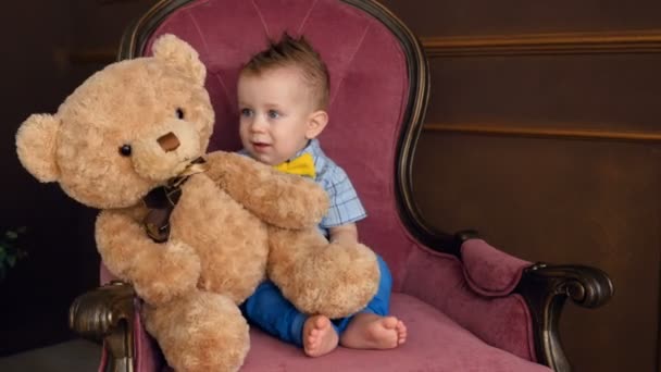 Маленький хлопчик і плюшевого ведмедика. Хлопчик штовхає плюшевого ведмедика. — стокове відео