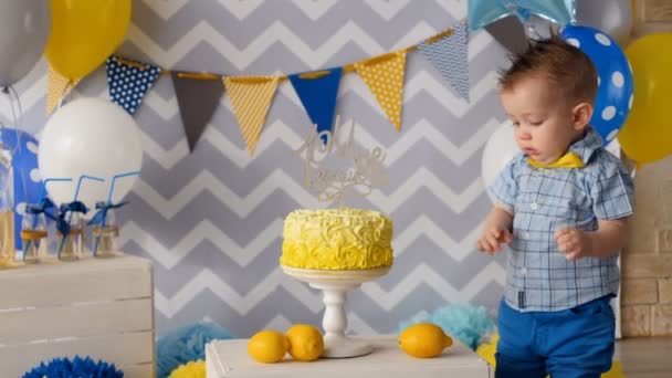 Il ragazzo sta toccando la sua torta di compleanno con un dito . — Video Stock