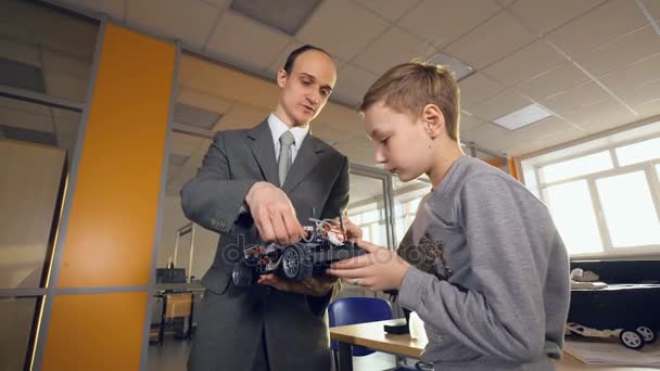 Вчитель показує студенту екологічно чисту майбутню машину. Електронний, водень, літій-іонний акумулятор автомобіля . — стокове відео