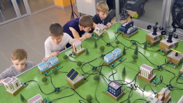 Grundschüler beschäftigen sich mit alternativen Energieprojekten am Prototyp einer Stadt. — Stockvideo