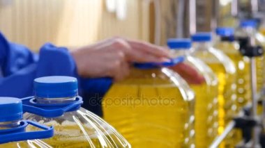 Ayçiçek yağı işleme fabrikası. İşçi düzeltme plastik şişe üzerindeki kolu. 4k.