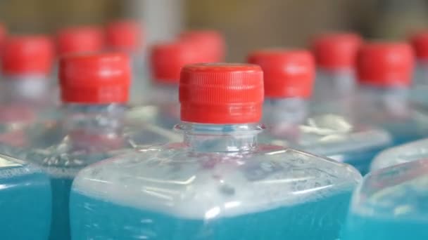 Convoyeur avec de nombreuses bouteilles avec couvercles bleu liquide et rouge. 4K . — Video