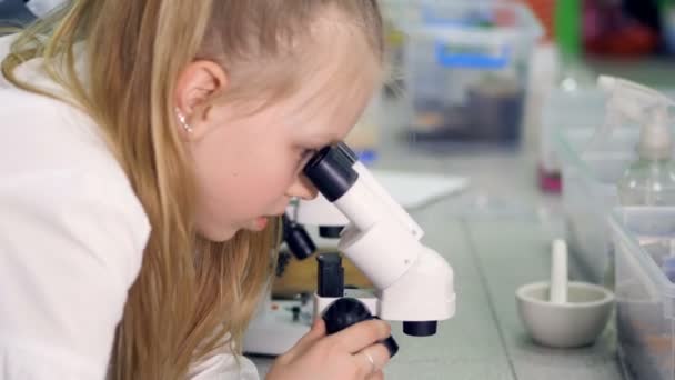 O grande plano da rapariga a olhar para a amostra no microscópio. 4K . — Vídeo de Stock
