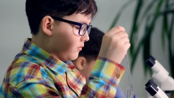 El primer plano del chico tomando muestras líquidas por el cuentagotas en el laboratorio de la escuela de ciencias. 4K . — Vídeos de Stock