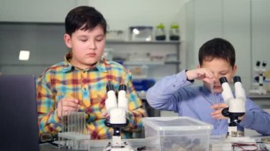 Genç bilim adamları çocuklar laboratuarda karşılıklı çalışır. Yakın çekim. 4k.