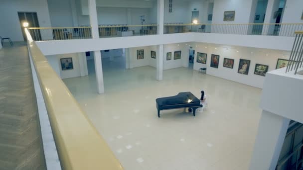 Девушка играет на пианино в картинной галерее — стоковое видео
