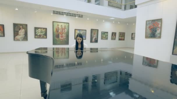 Menina tocando piano na galeria de arte — Vídeo de Stock