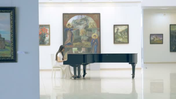 Жінка-піаністка грає на піаніно в галереї фотографій — стокове відео