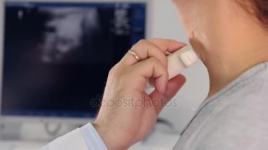 Doktor hasta boynunda bir ultrason cihazı ile inceliyor..