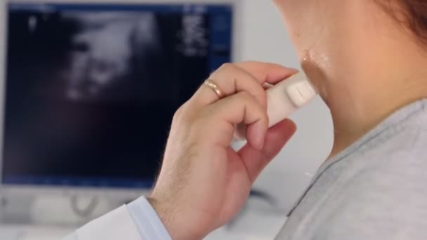 Lekarz bada jego szyi pacjentów z urządzenie ultradźwiękowe. — Wideo stockowe