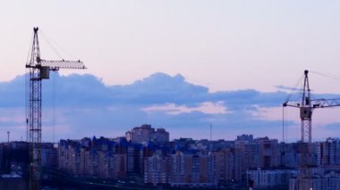 Gün batımında çalışma Crane. Arka plan üzerinde bir şehir binaları ile şantiye. Timelapse. 4k.