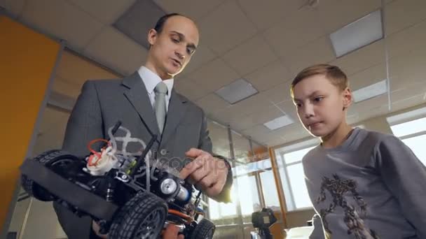 Учитель объясняет мальчику, как работает машина. . — стоковое видео