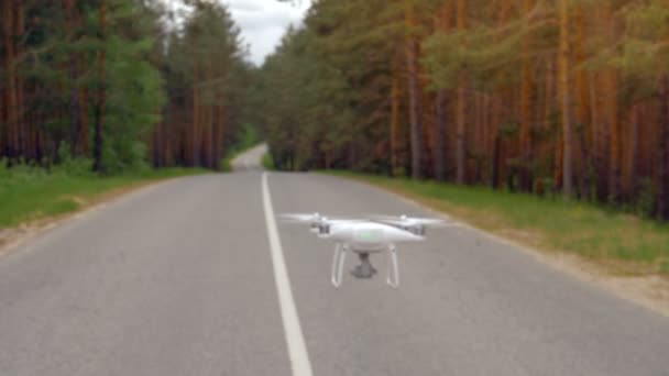 A quadcopter flying along the asphalt road. — Stock Video