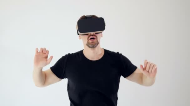 Чоловік у гарнітурі віртуальної реальності виглядає наляканим. Білий фон. 4-кілометровий . — стокове відео