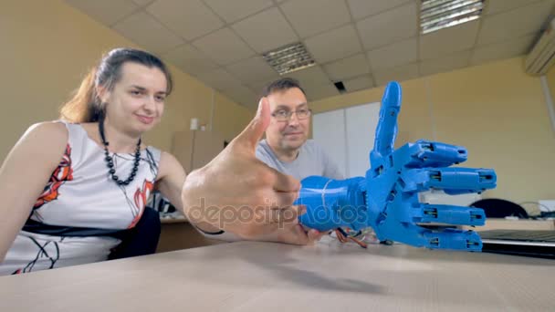 Ein Ingenieur zeigt einer Assistentin bionische Armbewegungen. — Stockvideo