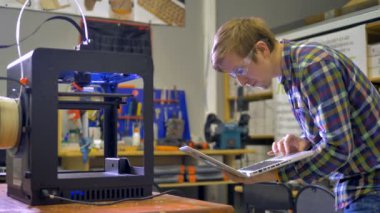 3d yazıcının çalıştığını ve adam laptop ekranında arıyor. 4k.