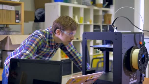 Мужчина наблюдает за процессом 3D-печати. 4K . — стоковое видео