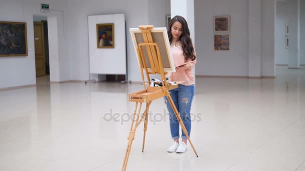 Girl painting a picture in art gallery. — Stock Video