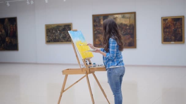 Girl painting on canvas in picture gallery. — Stock Video