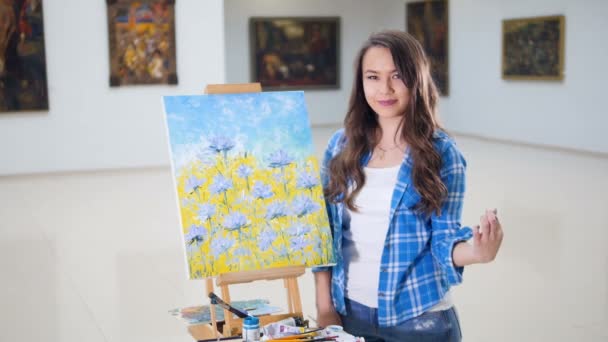 Krásná dívka stojící vedle malovaného obrazu. Portrét. — Stock video