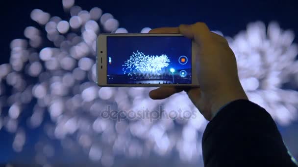 Mans hand is holding a phone and recording a video of fireworks. — Stock Video